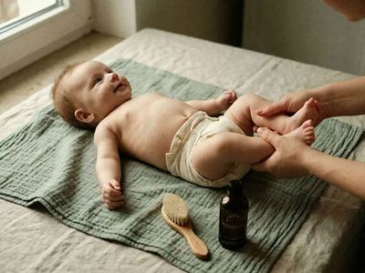 Baby auf einer Wickelunterlage wird gepflegt, daneben Holzbürste und bumwell Wundschutz Liquid