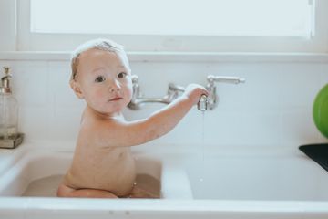 Ein Baby sitzt im Waschbecken und badet