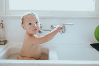 Ein Baby sitzt im Waschbecken und badet