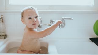 Ein Baby sitzt im Waschbecken und badet