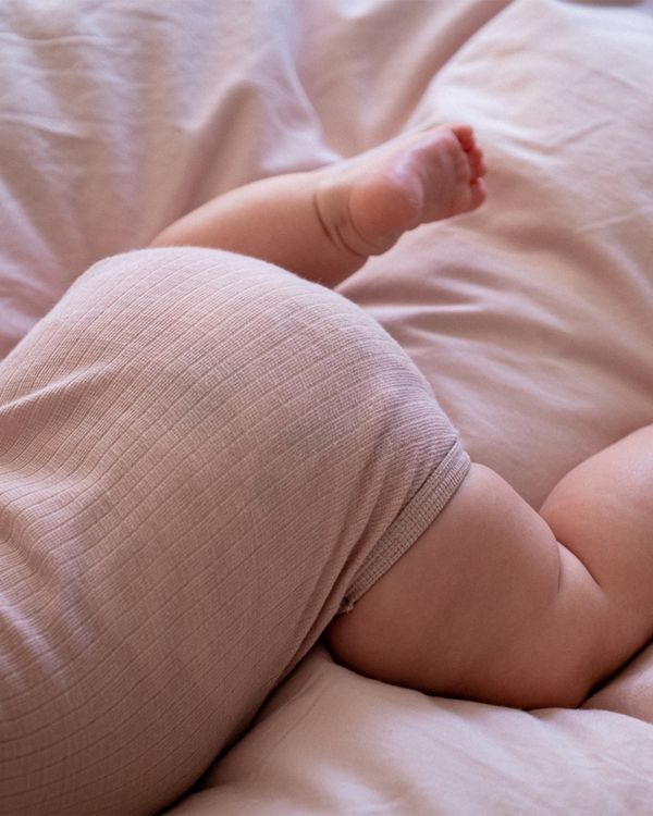 Säugling liegt bäuchlings auf dem Bett