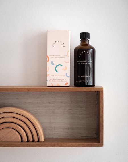 bumwell Baby-Wundschutz Liquid mit Verpackung im Kinderzimmer - Bio-Naturkosmetik in nachhaltiger Braunglasverpackung