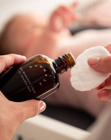 Mutter trägt bumwell Baby-Wundschutz Liquid auf Wattepad auf - Bio-Babypflege mit Schwarztee und Eichenrinde