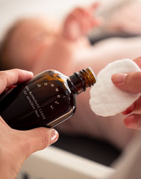 Mutter trägt bumwell Baby-Wundschutz Liquid auf Wattepad auf - Bio-Babypflege mit Schwarztee und Eichenrinde