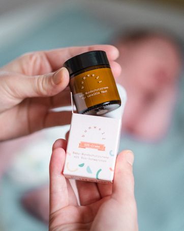 Mutter nimmt bumwell SOS Baby-Wundschutzcreme aus der Verpackung - Bio-Naturkosmetik für sensible Babyhaut