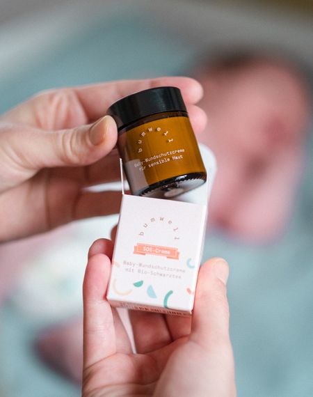 Mutter nimmt bumwell SOS Baby-Wundschutzcreme aus der Verpackung - Bio-Naturkosmetik für sensible Babyhaut