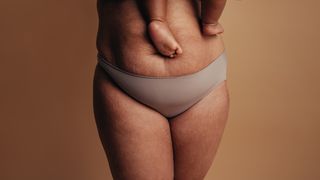 Frau mit postnatalem Bauch und Baby auf dem Arm